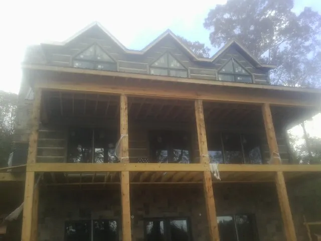 Dormers and porch framing on a large log home under construction — Roof Coating work by our crew in Blue Rock