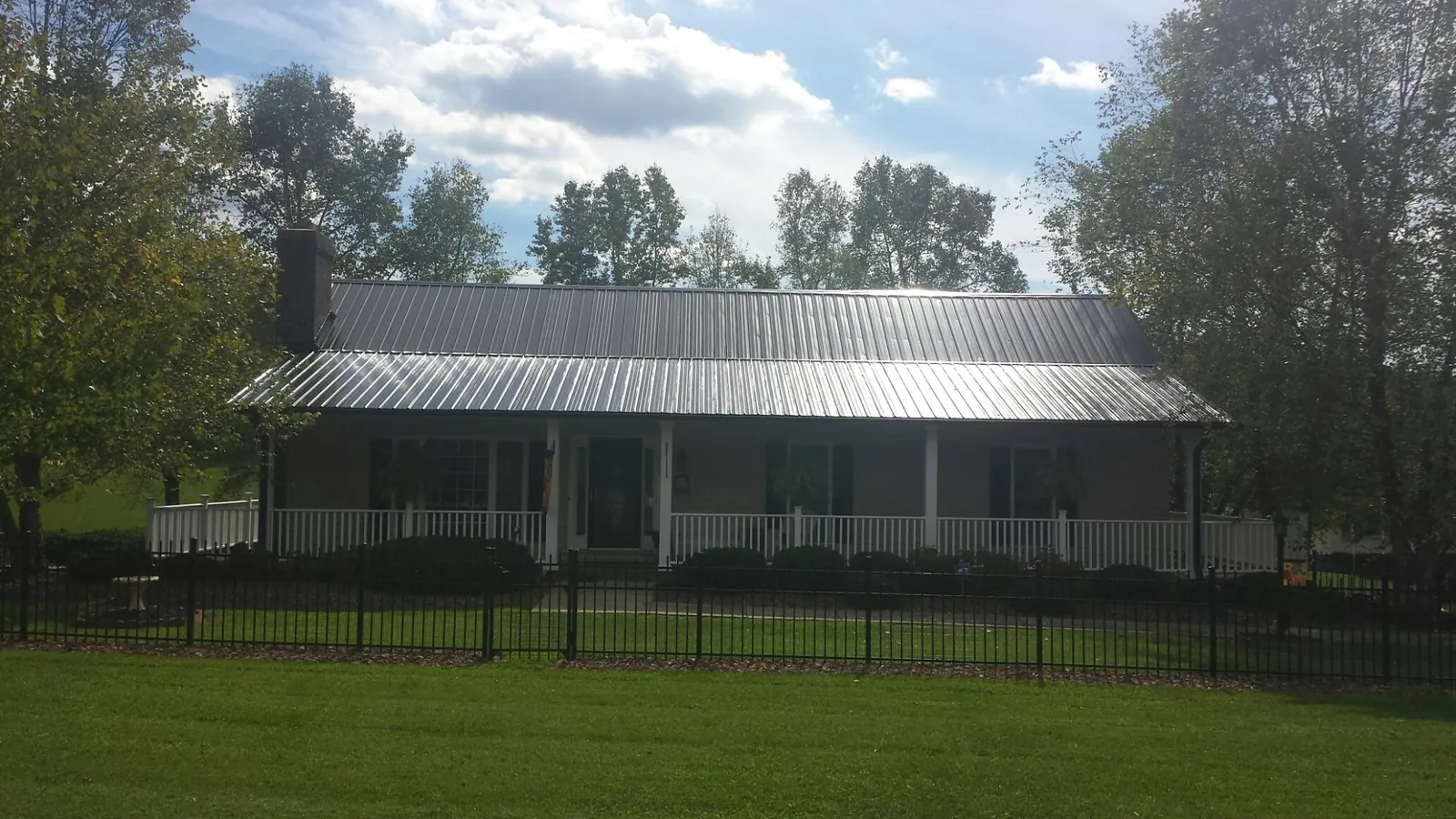Gray metal roof on a brick ranch with a full width front porch — Gutter Guard Installation work by our crew in Blue Rock