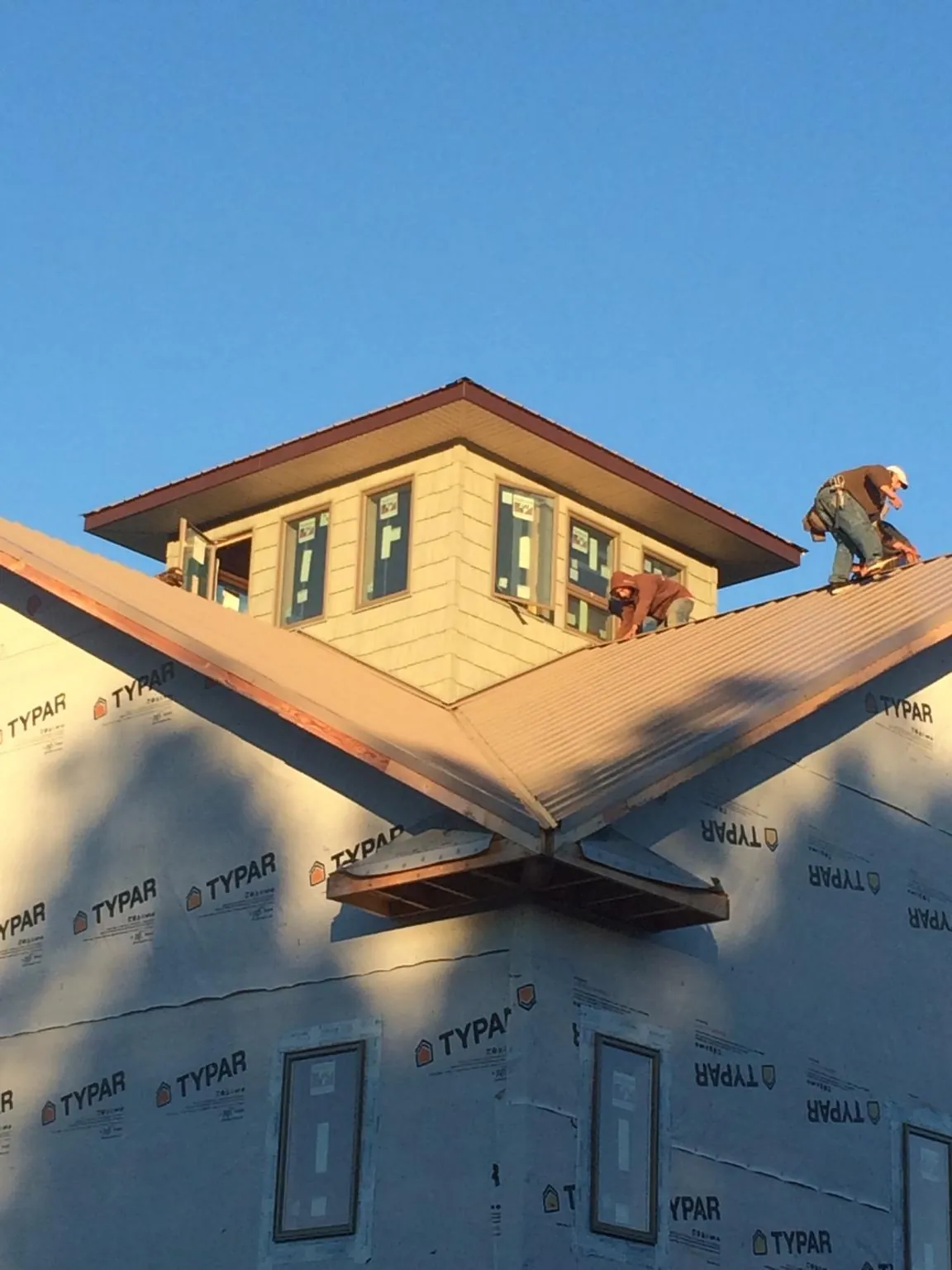 Roofers working around a rooftop cupola on a new metal roof at sunset — Roof Waterproofing in Blue Rock by Roofing Brothers